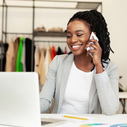 femme au téléphone avec un grand sourire, elle est devant son ordinateur