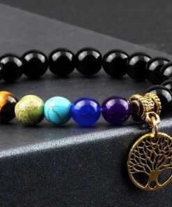 bracelet arbre de vie en or avec des pierres naturelles 7 chakras sur une table noir