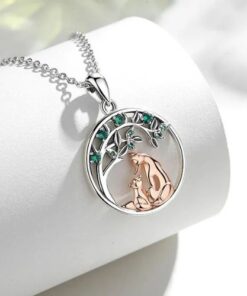 collier arbre de vie en argent avec feuilles vertes et louve posé sur un porte bijou