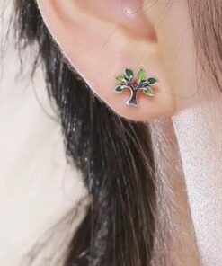 boucles d'oreilles arbre de vie en argent avec des touches de verts sur l'oreille d'une femme