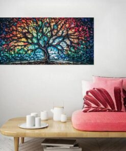 tableau arbre de vie coloré et abstrait sur un mur gris, avec un canapé en bois et des coussins rose